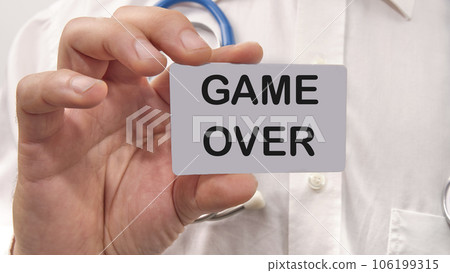 game over word on the card in a man's hand on the background of a white shirt game over word on the card in a man's hand on the background of a white shirt 106199315