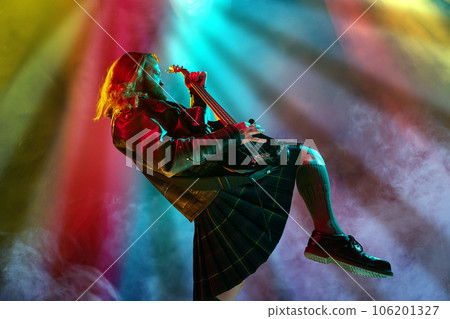 Rock and roll concert. Artistic, expressive man with long hair playing guitar and making performance, emotionally singing Rock and roll concert. Artistic, expressive man with long hair playing guitar and making performance, emotionally singing 106201327