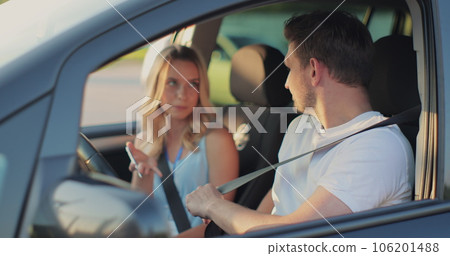 Young man and driving school instructor with clipboard talking in car. Man listening to instructor in car learning to drive. 106201488