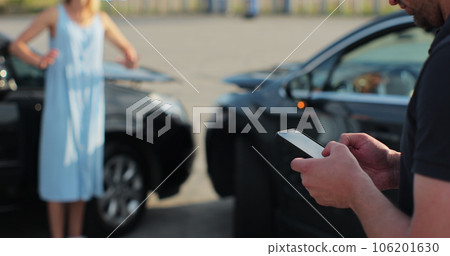 Man insurance agent inspects damage to a woman car and makes notes on a smartphone. Man inspecting broken car. Insurance concept. 106201630
