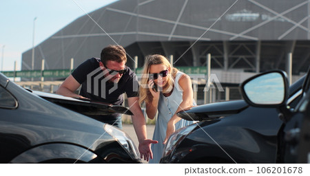 Woman driver using smartphone to call. Man driver looking on smashed broken car in accident. People are finding out the cause of the accident on the road. Car accident. 106201678