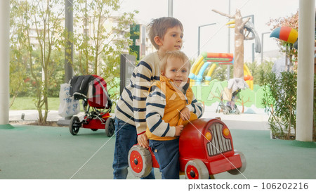 Older boy riding his little brother on the spring rider at kids playground. Older boy riding his little brother on the spring rider at kids playground. 106202216