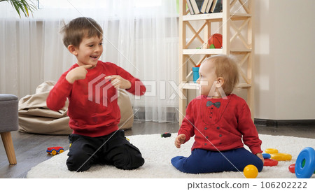 Funny shot of two little brother dancing on carpet in living room. Concept of child education, baby development, family having fun and playing games. Funny shot of two little brother dancing on carpet in living room. Concept of child education, baby development, family having fun and playing games. 106202222