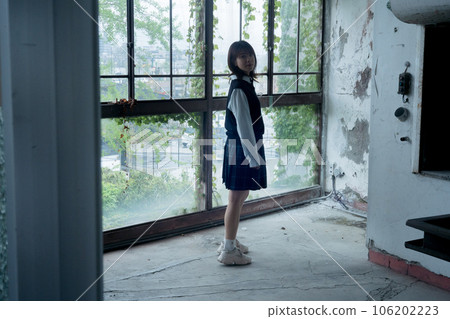 A high school girl standing in front of a large window at school A high school girl standing in front of a large window at school 106202223