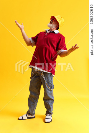 Full length portrait of attractive cheerful funny man staying with raising hands and smiling isolated over yellow color background 106202616