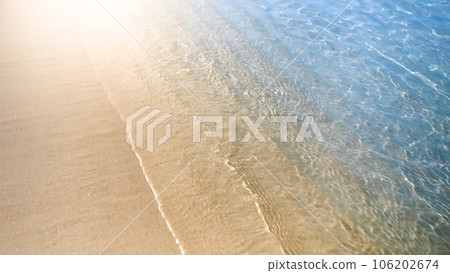 Slow motion of camera flying over calm sea waves rolling on sandy beach 106202674