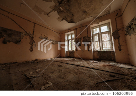 Spacious old room with weathered walls and big dirty windows in dilapidated building during daytime Spacious old room with weathered walls and big dirty windows in dilapidated building during daytime 106203996