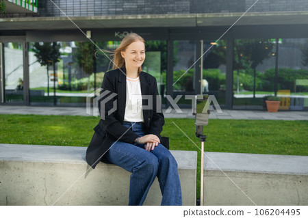 Young woman vlogger recording her daily video blog. Vlogger using a camera mounted on a tripod to record her video. Young woman vlogger recording her daily video blog. Vlogger using a camera mounted on a tripod to record her video. 106204495
