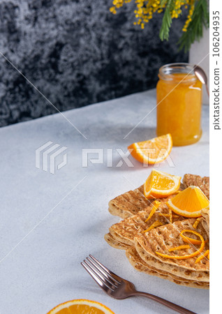 Folded baked French crepes or Russians blinis with orange slices and jam and copy space. Spring breakfast. Folded baked French crepes or Russians blinis with orange slices and jam and copy space. Spring breakfast. 106204935