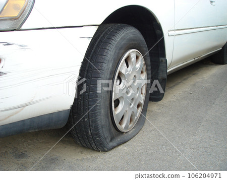 一輛白色汽車的車身被刺破的輪胎和划痕,特寫。 一輛白色汽車的車身被刺破的輪胎和划痕,特寫。 106204971