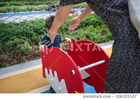 A little boy is playing on a swing with his mom. A little boy is playing on a swing with his mom. 106205387