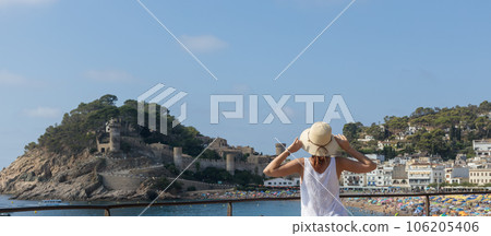 Woman in a hat on the background of the picturesque village of Tossa de Mar. Woman in a hat on the background of the picturesque village of Tossa de Mar. 106205406