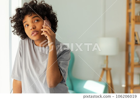 African american girl talking on smartphone at home indoor. Young woman with cell phone chatting with friends. Smiling teen girl making answering call by cellphone. Lady having conversation by mobile African american girl talking on smartphone at home indoor. Young woman with cell phone chatting with friends. Smiling teen girl making answering call by cellphone. Lady having conversation by mobile 106206019