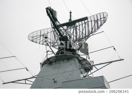 Radar on a warship on a metal structure against a gray sky. A lot of wires and metal parts. Rainy gloomy weather. Radar on a warship on a metal structure against a gray sky. A lot of wires and metal parts. Rainy gloomy weather. 106206141