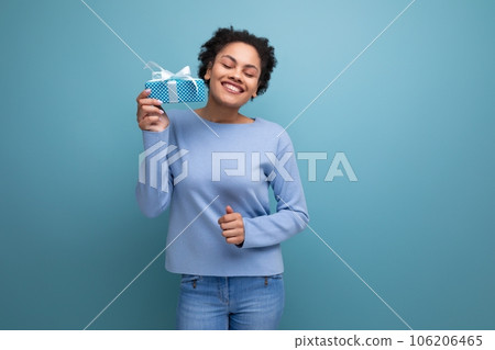 happy young brunette woman with afro curls holding gift box 106206465
