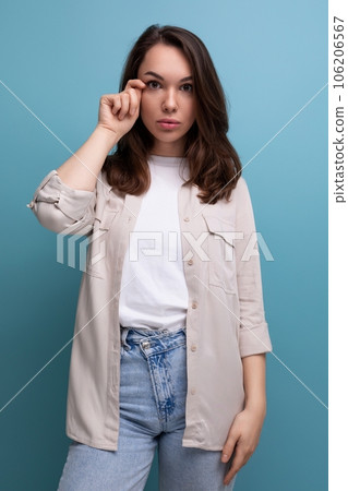 pretty european young brunette woman in shirt and jeans on blue background pretty european young brunette woman in shirt and jeans on blue background 106206567