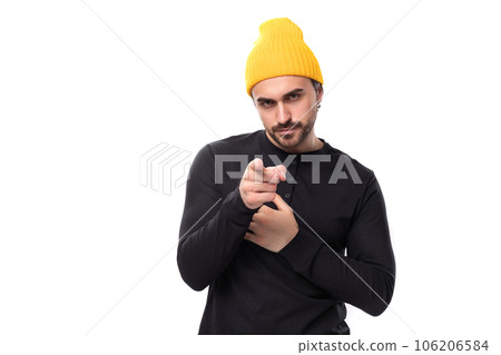 young brunette handsome caucasian male model with a beard dressed in a black jacket and a yellow cap 106206584