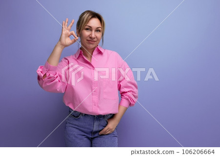 well-groomed young blond caucasian woman model with a ponytail hairstyle put on a pink shirt and 106206664