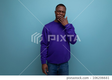 charming cute young african guy in a blue sweatshirt on the background with copy space charming cute young african guy in a blue sweatshirt on the background with copy space 106206681