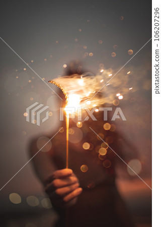 A woman holding out a hand-held fireworks in front of her 106207296
