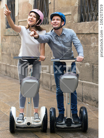 Young couple guy and girl walking on segway in streets of european city 106207859