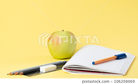 Workbook with pen and pencils for studying, apple for a snack Workbook with pen and pencils for studying, apple for a snack 106208069
