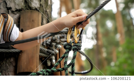 Closeup of child hand holding rope and safety hook for mountain climbing and alpinism 106208121