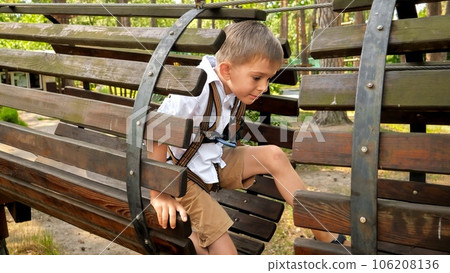 Little boy crawling through wooden pipe or tunnel on playground at park. Active childhood, healthy lifestyle, kids playing outdoors, children in nature 106208136