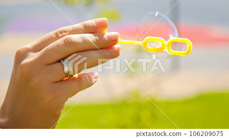 Closeup of wind blowing soap bubbles at park. 106209075