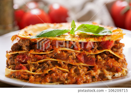 plate of lasagna with green basil 106209715
