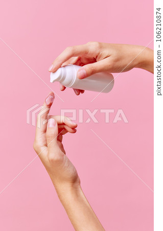 Close up side view photo of woman's hand squeezing gel for hands from unmarked bottle with dispenser on finger. Cropped. Concept of body care. Close up side view photo of woman's hand squeezing gel for hands from unmarked bottle with dispenser on finger. Cropped. Concept of body care. 106210874
