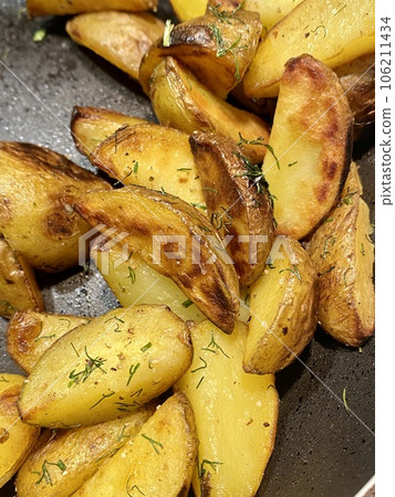 Potato wedged, oven roasted with dill, a close up in a baking tray Potato wedged, oven roasted with dill, a close up in a baking tray 106211434