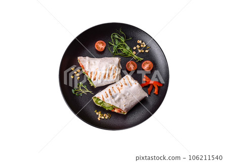 Delicious fresh shawarma with tomatoes, peppers, cucumber on a dark concrete background Delicious fresh shawarma with tomatoes, peppers, cucumber on a dark concrete background 106211540