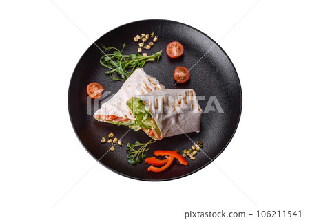 Delicious fresh shawarma with tomatoes, peppers, cucumber on a dark concrete background Delicious fresh shawarma with tomatoes, peppers, cucumber on a dark concrete background 106211541