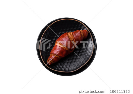 Delicious crispy croissant with chocolate on a black ceramic plate Delicious crispy croissant with chocolate on a black ceramic plate 106211553