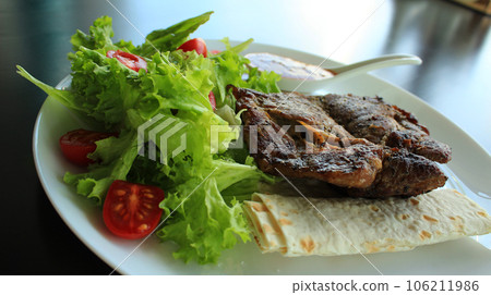 Fried Meat With Tomatoes And Vegetables On A White Plate 106211986