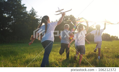 children run through the meadow in the park with toys in their hands. happy family kid dream concept. a group of little kids have fun together and play with flying kites toy lifestyle airplane children run through the meadow in the park with toys in their hands. happy family kid dream concept. a group of little kids have fun together and play with flying kites toy lifestyle airplane 106212372