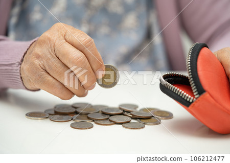 Asian senior woman holding counting coin money in purse. Poverty, saving problem in retirement. 106212477