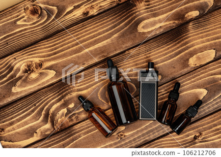 Vape and vape juice bottles on brown wooden background 106212706