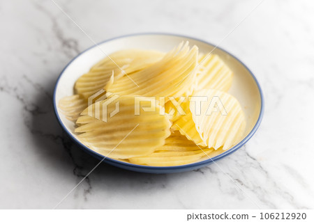 Potato and potato chips placed on a marble slab. Potato and potato chips placed on a marble slab. 106212920