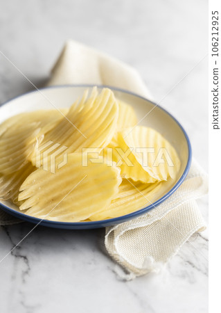 Potato and potato chips placed on a marble slab. Potato and potato chips placed on a marble slab. 106212925