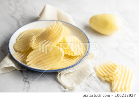 Potato and potato chips placed on a marble slab. 106212927