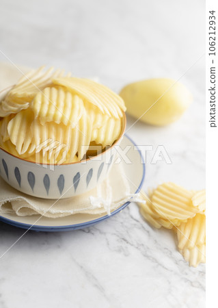 Potato and potato chips placed on a marble slab. 106212934
