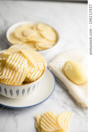 Potato and potato chips placed on a marble slab. 106212937