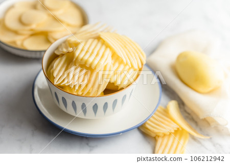 Potato and potato chips placed on a marble slab. 106212942