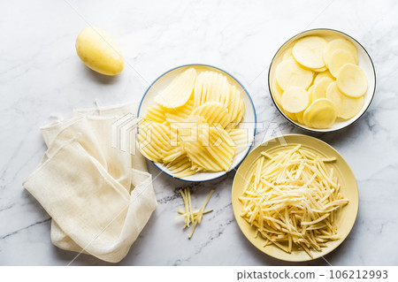 Potato, shredded potato, and potato chips placed on a marble slab. 106212993
