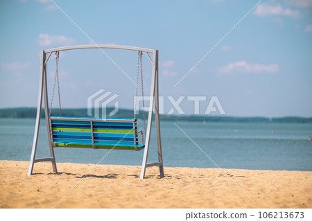 Empty metal swing on the sandy beach near the sea Empty metal swing on the sandy beach near the sea 106213673