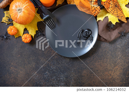 Halloween table setting. Blank black plate with decoration pumpkins, autumn leaves, spiders on a stone background. Card or menu template. Top view. Copy space. 106214032