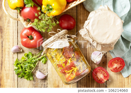 Healthy homemade fermented food. Salad tomatoes with vegetables on a rustic table. Home economics, autumn harvest preservation. View from above. 106214060