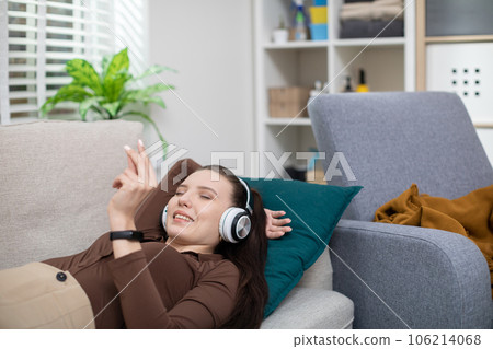 The girl is lying on the couch and one hand is held under her head 106214068